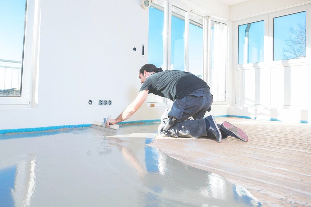 A Houston contractor installs self-leveling underlayment, preparing the subfloor for commercial polished cement floors.