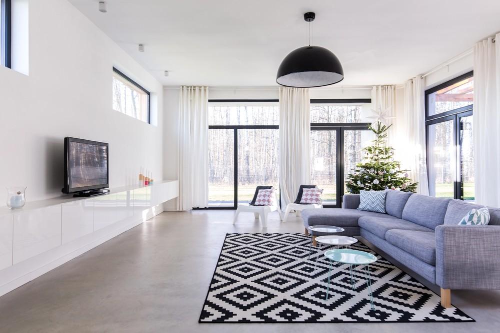 Modern living room styled by polished concrete contractors Houston featuring a gray sectional and geometric rug.