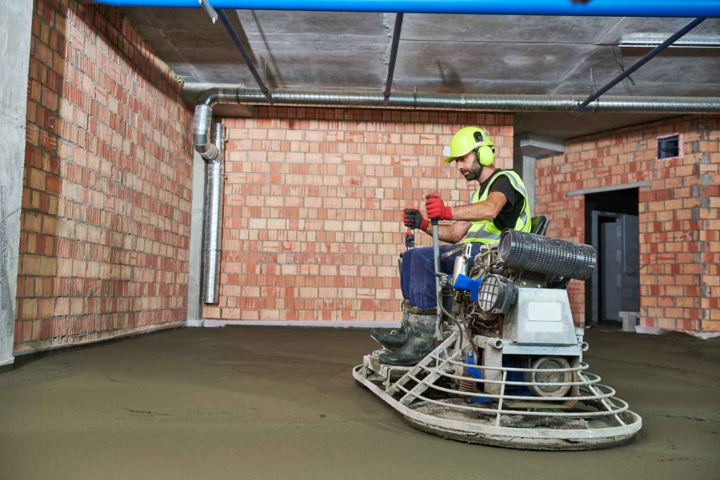 Industrial ride-on troweling machine finishing a large surface for professional shiny cement flooring Houston.