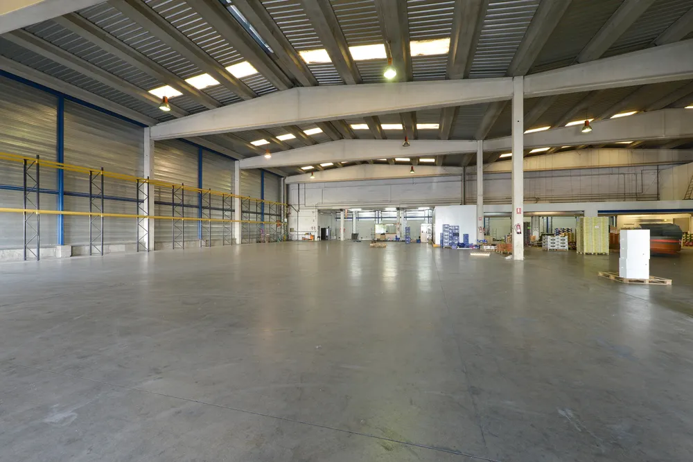 Clean polished concrete flooring Houston facility with steel trusses, storage racks, and bright industrial workspace.
